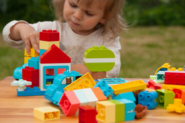 Colorful plastic toys and baby in blur. Construction toys. Early development concept. Baby playing with colorful plastic toys. Baby playing in playground. Preschool concept 