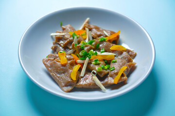 Buckwheat dumplings with greenery served on a plate over blue background. Tasty dish isolated on blue.