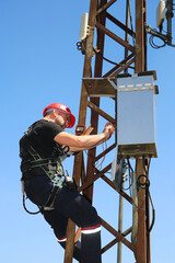 Engineer in red helmet with multimeter on the electric pole