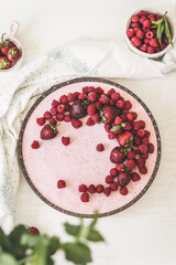 Beautiful berry cream pie with strawberries, raspberries in a glass dish on white table, top view, flat lay
