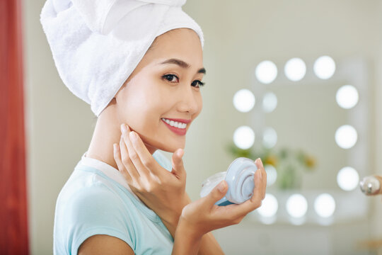 Happy Smiling Young Vietnamese Woman Applying Night Cream On Her Face After Taking Shower