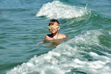 A happy boy is swimming in the sea . Children's holiday at the sea