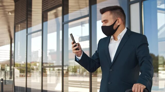 Elegant businessman wearing protective mask in airport. Young mail entrepreneur in formalwear. Pandemic, new rules of control, business trip and traveling.