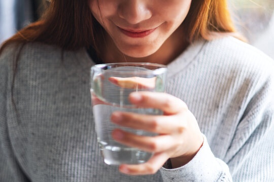 Closeup image of a beautiful young asian woman holding a glass of water to drink
