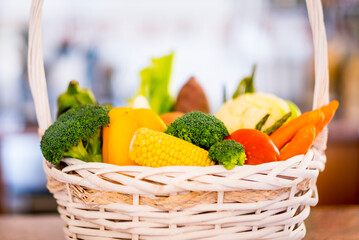 Close-up of white basket full of different kind of fresh raw vegetables. Healthy eating concept and detox diet. Vegan and vegetarian food.
