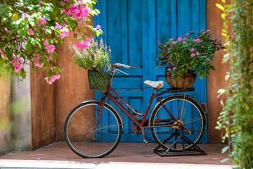 Vintage bike with basket full of flowers next to an old building in Danang, Vietnam, close up