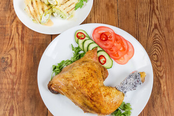 Fried chicken leg with vegetables on rustic table close-up