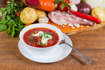 Serving of red beetroot borscht against the its raw ingredients
