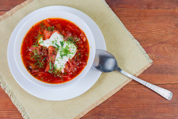 Red borscht in bowl with spoon on table, top view