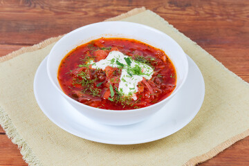 Red beetroot Ukrainian borscht in white bowl on rustic table