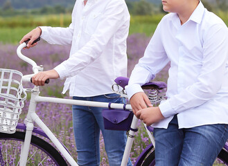 Teenage boys in white shirts ride a retro bicycle in a lavender field. Vacations and summer. Travel and tourism concept.