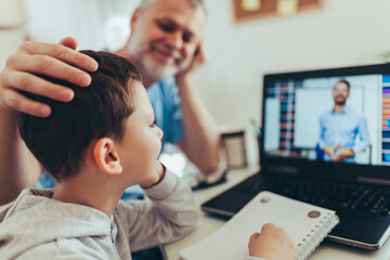 Schoolboy educate online. Father helps his son with home work. Boy in video conference with teacher...