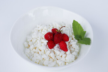 fresh diet curd homemade in a white plate with ripe strawberries and mint leaf on white background from boards. healthy breakfast option