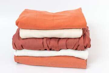 Clothes neatly folded into stack on white background, front view