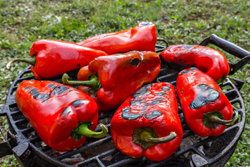 Close-up of roasted fresh red pepper on the grilling Pan, with gras in background, in the backyard - 362498040