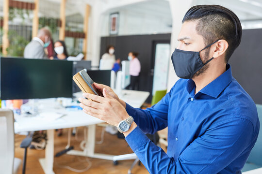 Young businessman with smartphone and face mask