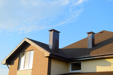 The roof of the house is made of sheets of brown metal tiles with a pipe