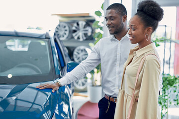 just imagine us on the road. portrait of happy african american couple checking out a car in modern...
