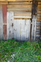A wooden door on the old wooden wall of a log house