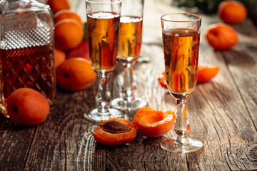 Apricot liquor and fresh apricots on a old wooden table.