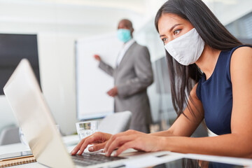 Businesswoman with face mask works on laptop