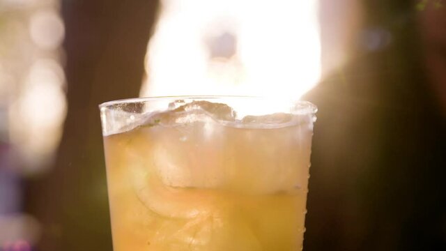 Close up of barista preparing a cocktail with ice by the beach. Sunset by  the sea