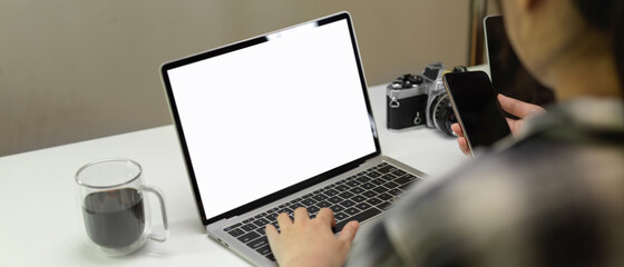 Female freelancer working with mock-up laptop and smartphone on minimal office desk