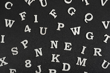 Letters of English alphabet on black background. Seamless black and white pattern of randomly placed letters