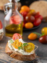 Delicious snack o bruschetta on wooden cut board ,grilled bread slices with cream cheese and different tomato cherry  garnished with fresh basil leaves