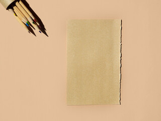 mock up. round pack of colourful wooden pencils  and craft paper sheet on beige background. top view, copy space.