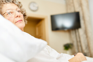 Kranke Seniorin liegt im Bett im Altenheim