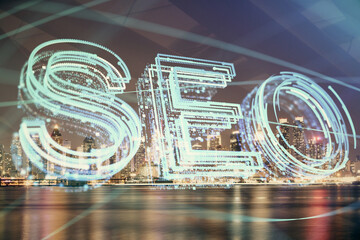 SEO hologram on city view with skyscrapers background double exposure. Search optimization concept.