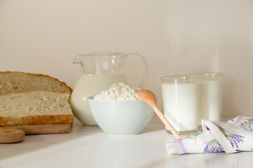 Milk in a glass jar, cottage cheese and  bread on the table. White background.