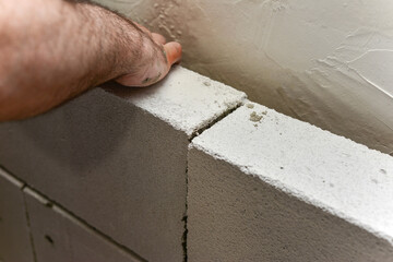 Worker lay foam block on mortar for building a wall in a house.