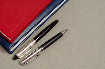 Silver fountain pen with leather notebook on office gray desk. Red book and pen. Business concept