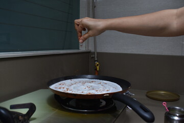 sprinkling indian spices masala on hot dosa with hands on non stick pan