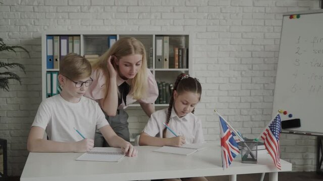 young teacher helping pupil leaning and explaining mistakes. Teacher between two students,. Tutoring