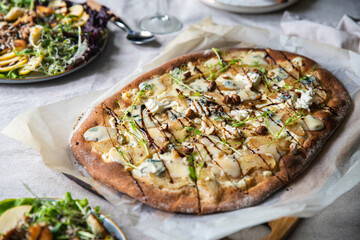 Table served with homemade oval shaped pear & gorgonzola pizza on baking paper and turkey and apple salad..