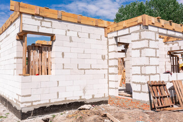 House under construction, walls of gas concrete blocks, wooden reinforcement and concrete foundation.