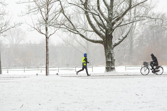 A man running in the Amsterdam Vondelpark on a cold and snowy winter day in december in the Netherlands.