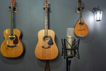 A home studio with a condenser microphone in the foreground and other musical instruments blurred slightly in the background