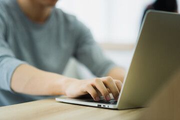 A man in casual outfit using and typing laptop for working at home in the morning day
