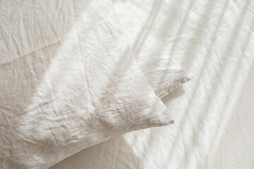 White linen textile bedclothes. Pile of pillows. Cozy bedroom interior and beautiful morning light....
