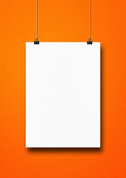White poster hanging on an orange wall with clips