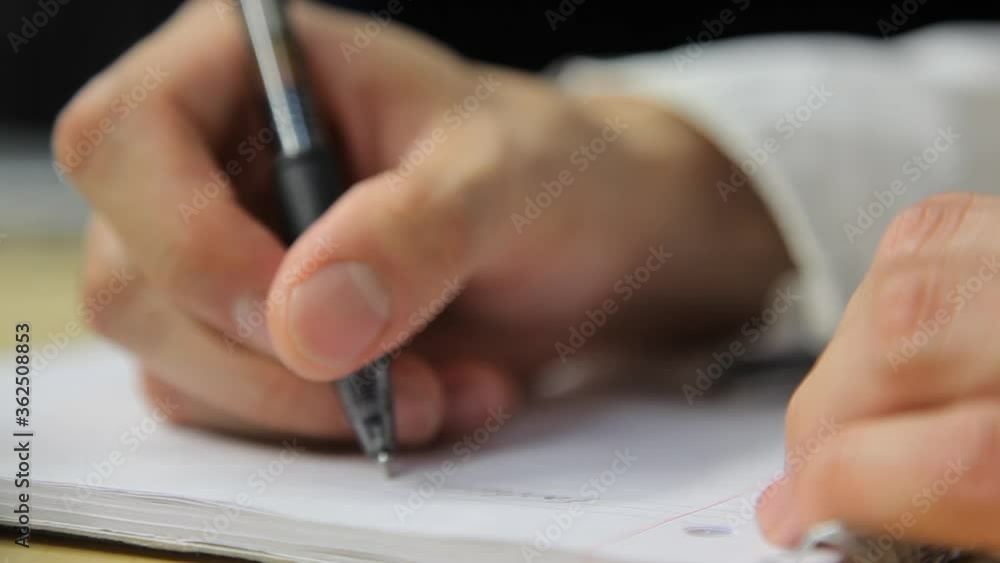 Poster low angle close up view of hand writing notes in notebook with pen. person starts to write on new pa