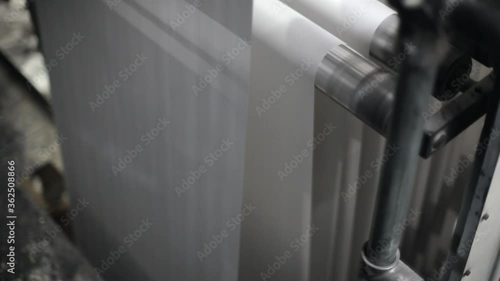 Poster paper roll rolling on rollers in printing press machine closeup detail