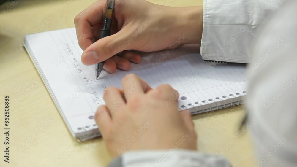 Aufkleber student taking notes in class taps pen on notebook before writing with pen. recording information on