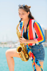Beautiful woman playing a golden saxophone outdoors. Street music and lifestyle concept.
