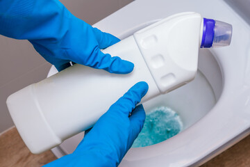 Clean toilet with cleaning agent bleaching gel and a gloved hand