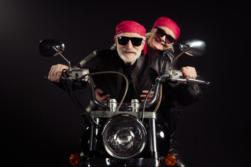 Fototapeta na wymiar Photo of two cool old bikers grey hair man lady couple drive vintage chopper traveling together feel young wear rocker leather jacket outfit bandana isolated black color background